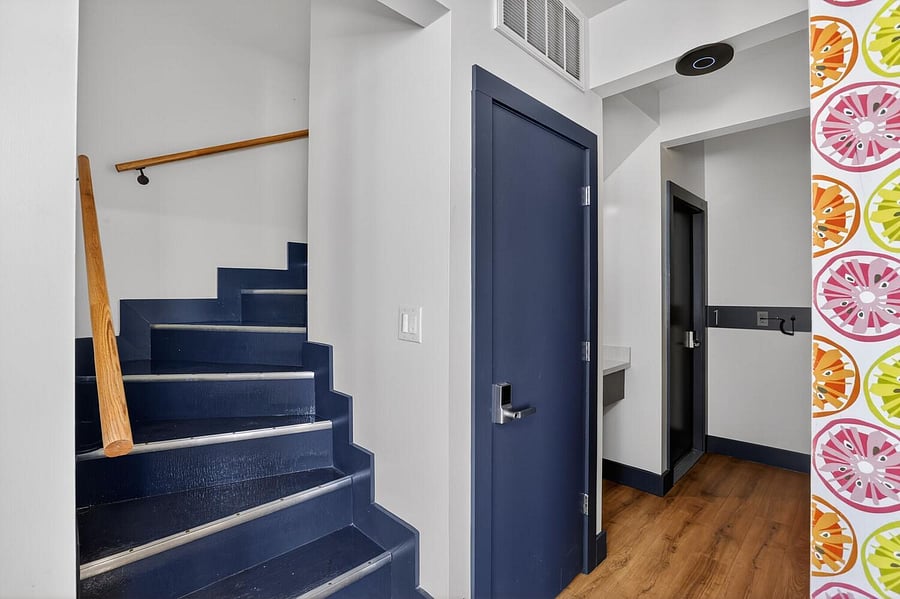 Clean entry hallway with wood-look flooring, stair access, and a built-in coat hook rail for everyday convenience.