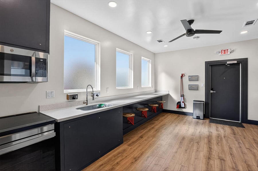 Eat-in kitchen with long prep counter, undermount sink, stainless microwave, and bar seating beneath oversized windows.