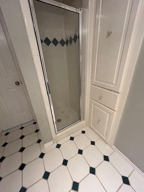 Shared bath has cabinetry for storage and a step-in shower.