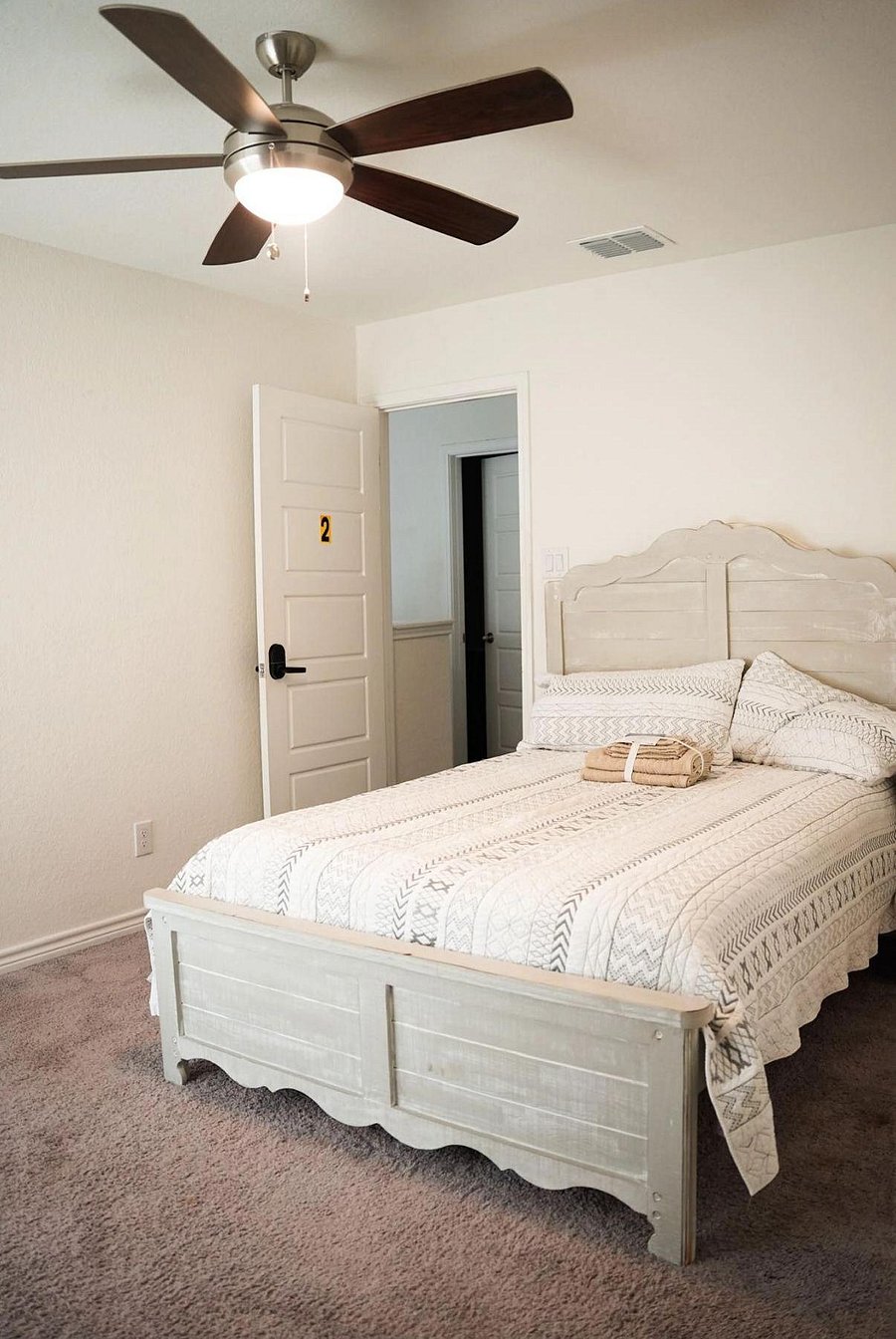 Furnished bedroom with a full bed, ceiling fan with light, and soft carpet, plus easy access to the hallway and bath.