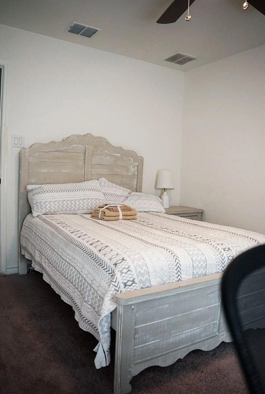 Furnished bedroom with a full-size bed, matching nightstand and lamp, plus a ceiling fan for added comfort.