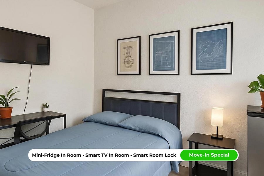 Light-filled queen room featuring a work desk + chair, Smart TV, mini fridge, and central A/C for everyday comfort.