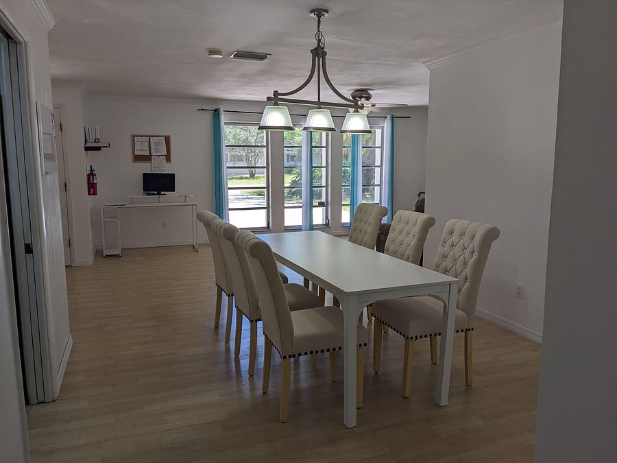 Dedicated dining area with seating for six, pendant lighting, and large windows overlooking the yard.