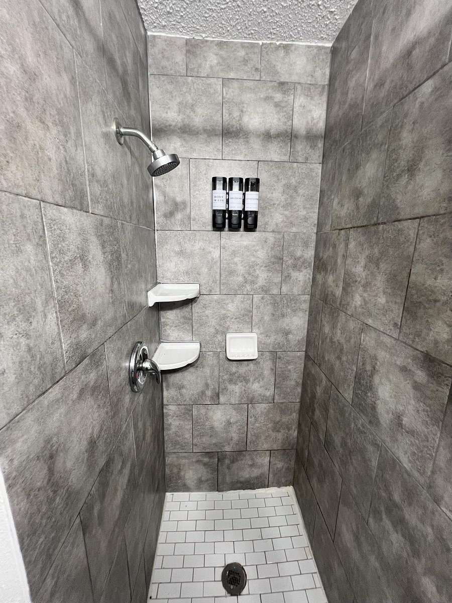 Tile-walled walk-in shower with built-in niche storage, corner shelves, and a tiled floor for easy upkeep.