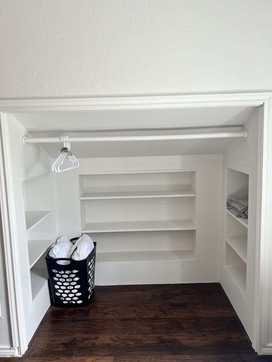 Built-in closet storage with hanging rod and multiple shelving sections for clothing, linens, and personal items.