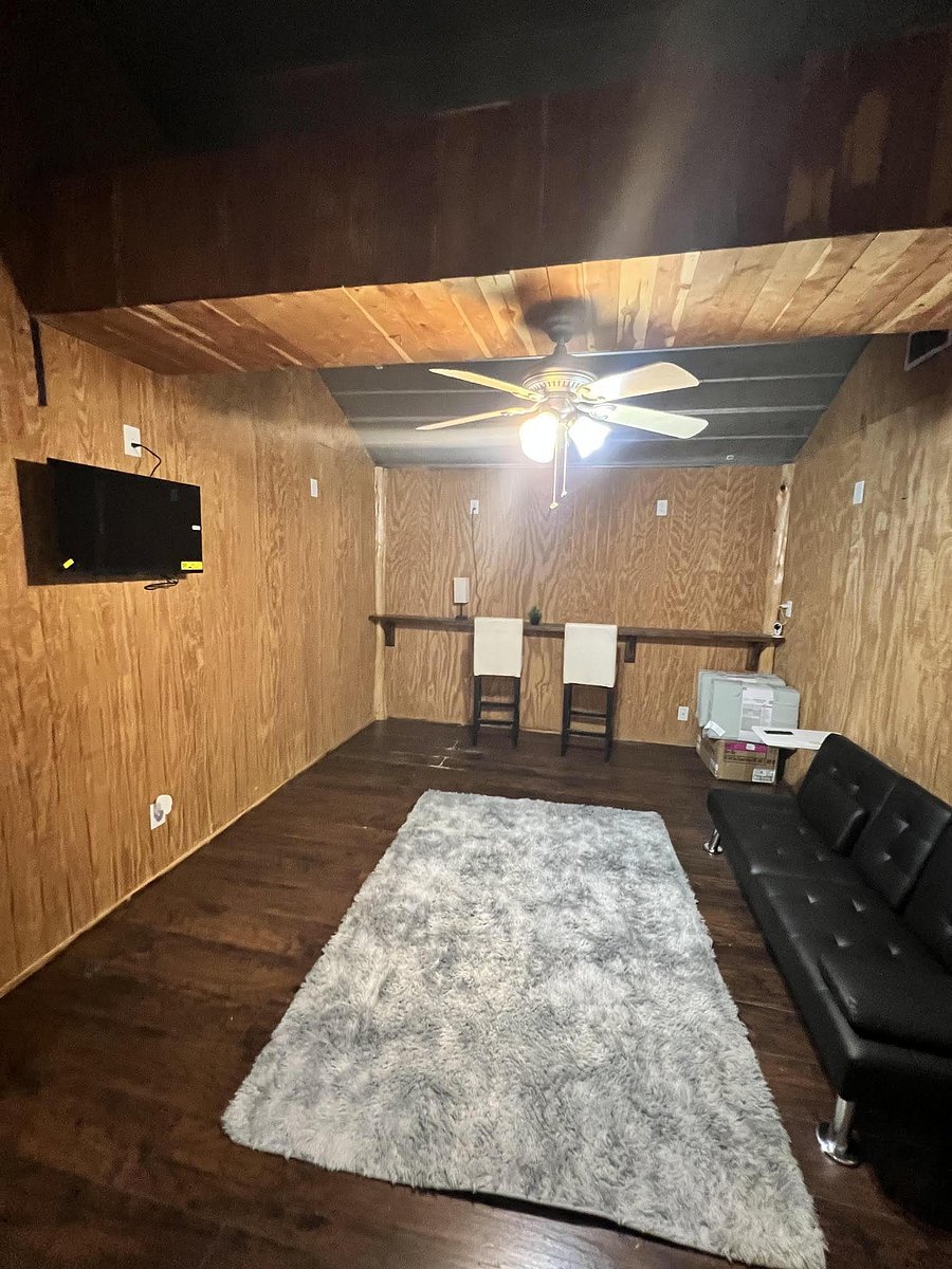 Flexible common room with mounted TV, ceiling fan, and open floor space for lounge seating or a small work area.