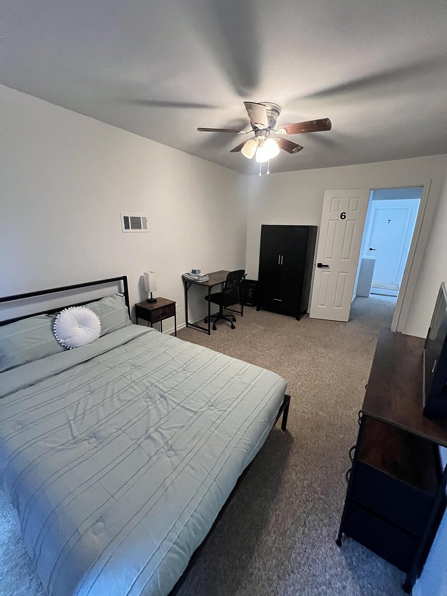 Furnished bedroom featuring a ceiling fan, bed and nightstand, dedicated desk area, and wardrobe storage with nearby hall acc