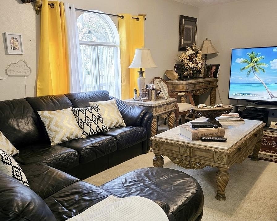Inviting living room with a large sectional, arched window with drapes, and ample space for relaxing and entertaining.