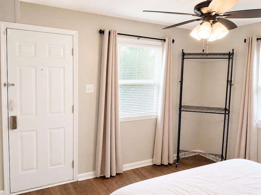 Bedroom with 2 large windows, block out drapes, ceiling fan with light, and a rolling open closet rack and private entrance.