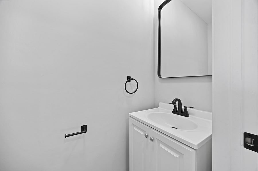 Clean bathroom vanity with ample counter space, under-sink storage, and a framed mirror with matte-black fixtures.