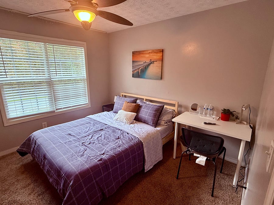 Bright second-floor bedroom with large window and workspace