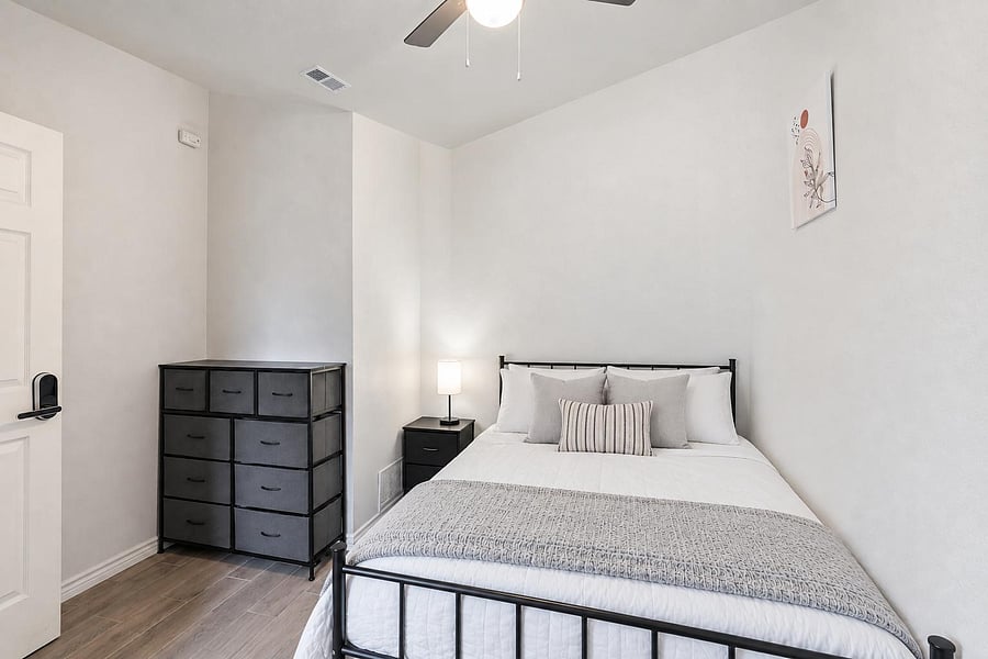 Private bedroom with a full bed, bedside table and lamp, and a multi-drawer storage unit for everyday organization.