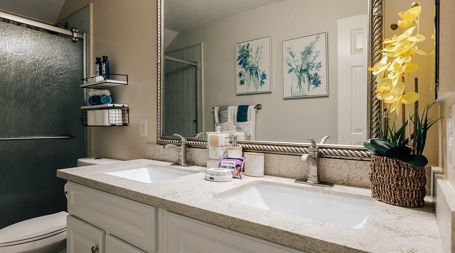 Well-appointed bath with a double-sink vanity, wide counter space, and a tub/shower combo with built-in shelving.