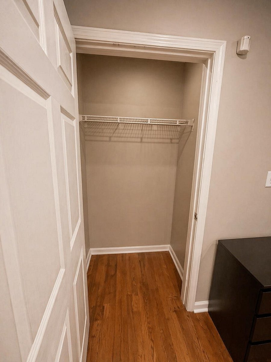 Bedroom closet with a hanging shelf and open floor space for luggage, bins, or a compact dresser.