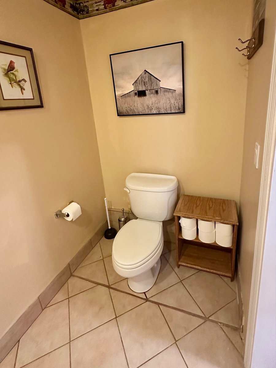 Large toilet/vanity room with good lighting and tile flooring.