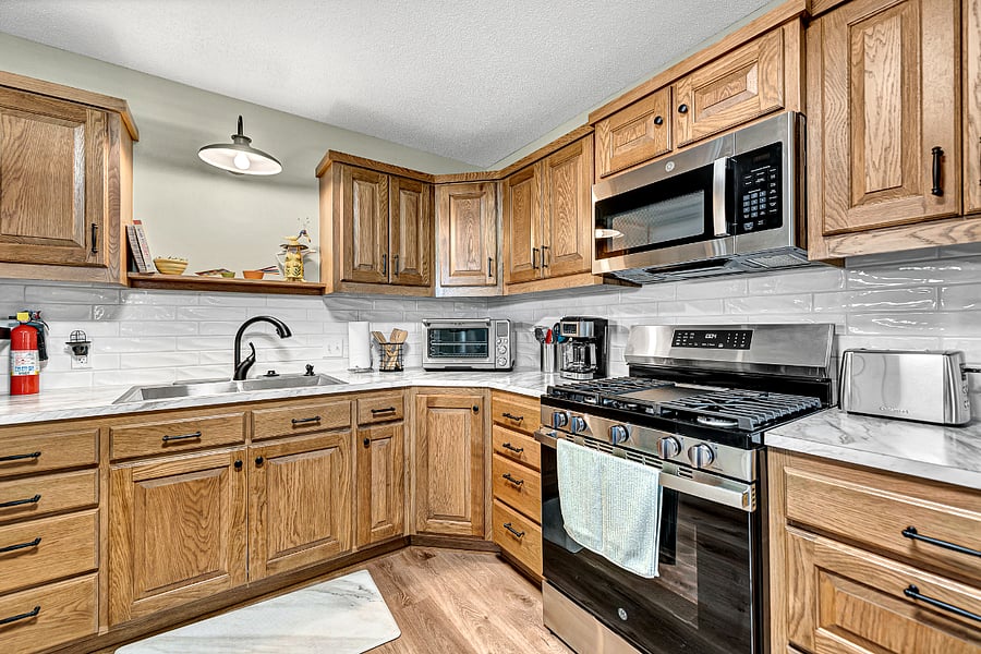 Full sized Whirlpool refrigerator, with ice maker. Custom, new cabinets, 5 burner gas range, lots of cookware and utensils.