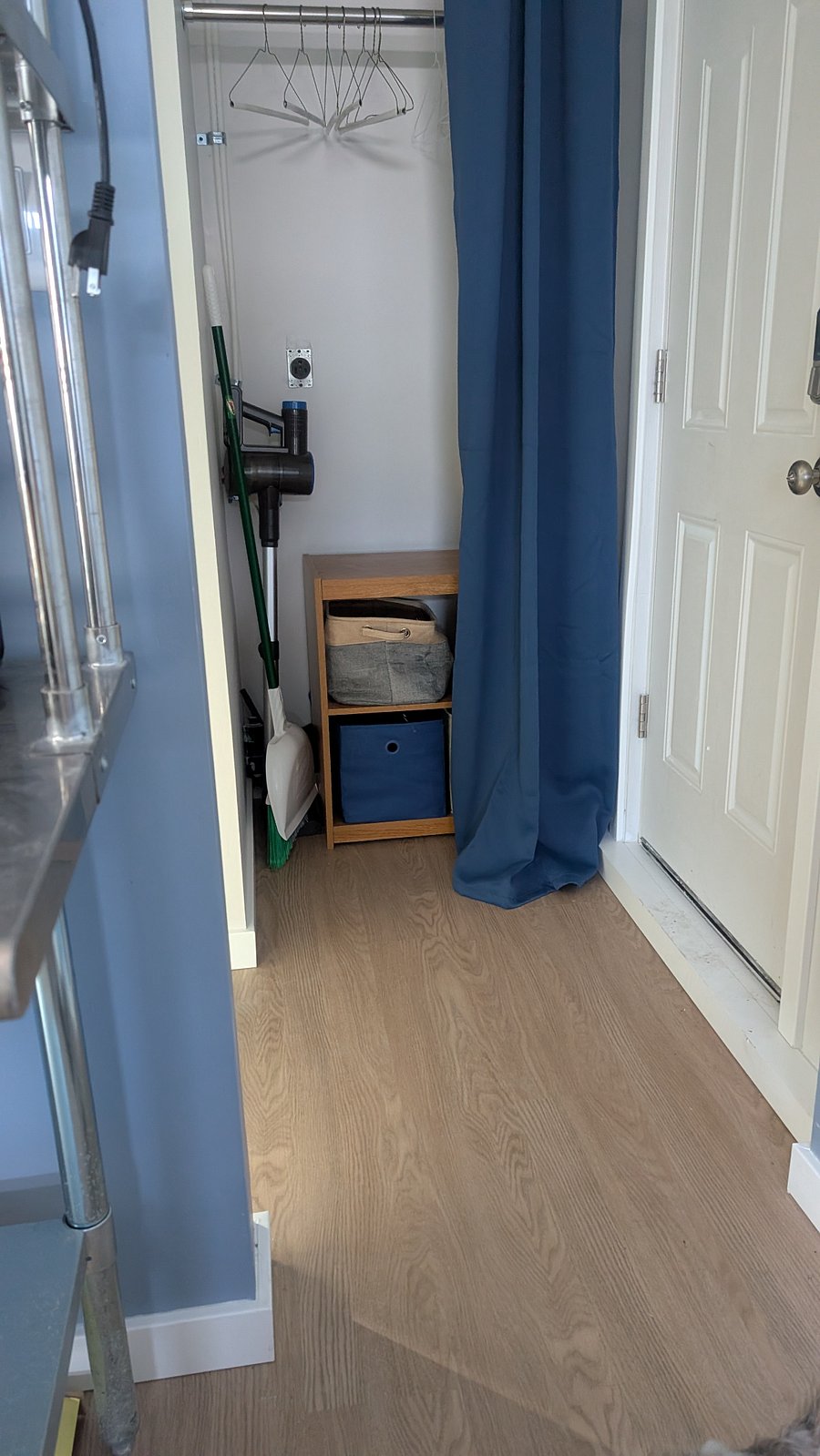 This is the only closet space in the garage apartment. This closet is right as you turn from the main area into the bathroom. You can see it from the main area of the room. It has a blue curtain. Two shelves. Hanging space for clothes above the shelves. You will see a door on the right of the photo. That door goes into the other property's yard. So that door stays closed - providing privacy for the tenant in the main house, who uses that yard.