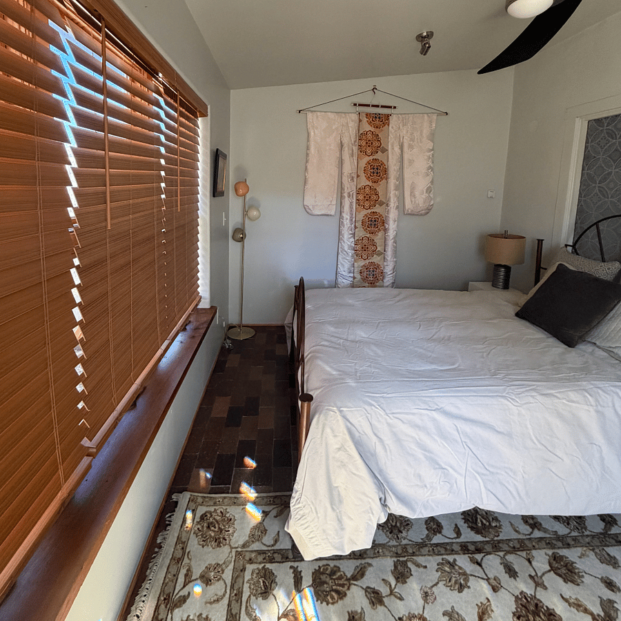 Bedroom showing window blinds that open to the yard. The windows open with screens.