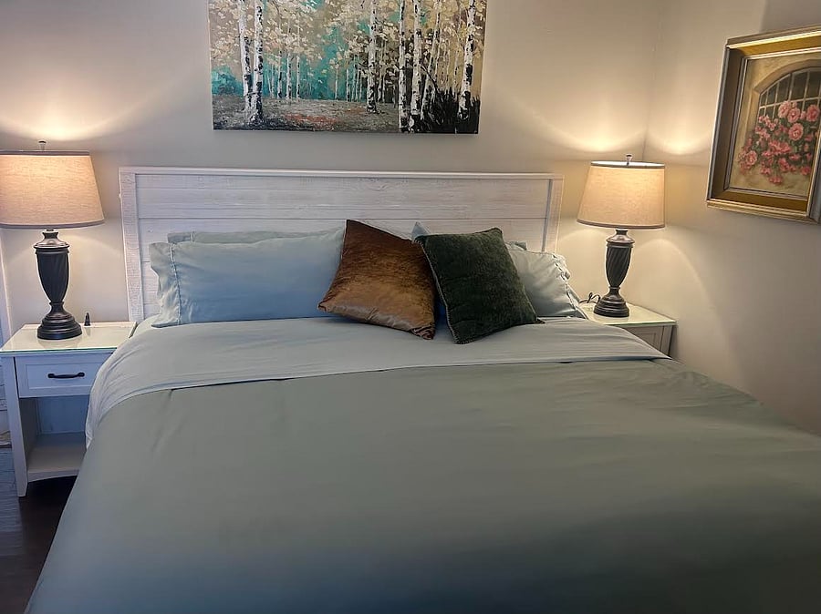 Comfortable and inviting bedroom with plush bedding, warm lighting, and a relaxing atmosphere
