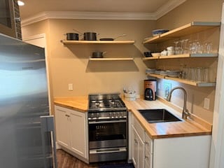 4-burner gas stove and stainless sink in fully furnished kitchen.