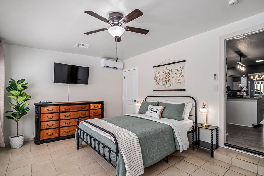 Third Bedroom  Queen-size farmhouse-style bed, our largest and most private room, featuring a step-down layout, independent AC/heating unit, walk-in closet, rustic charm, a ceiling fan, wall-mounted Smart TV, extra linens, and its own private entrance for added comfort and seclusion.