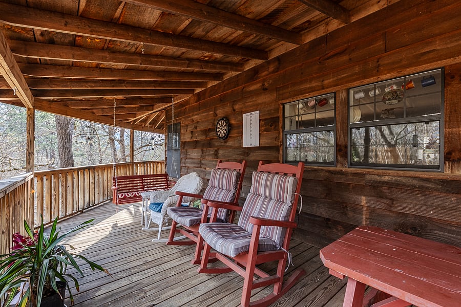 Comfortable padded rocking chairs next to picnic tables and dartboard. 
