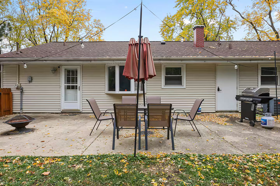 Outdoor patio table set with umbrella, grill and fire pit. Fenced backyard.