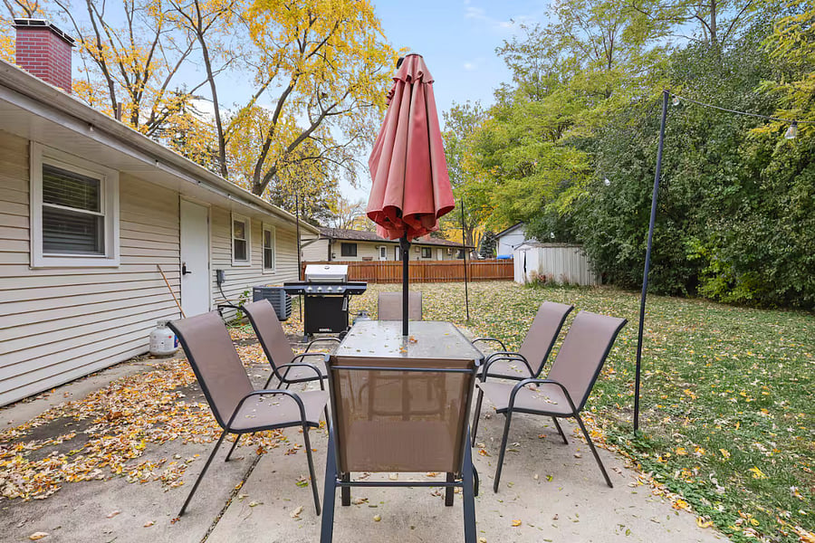 Outdoor patio table set with umbrella, grill and fire pit. Fenced backyard.