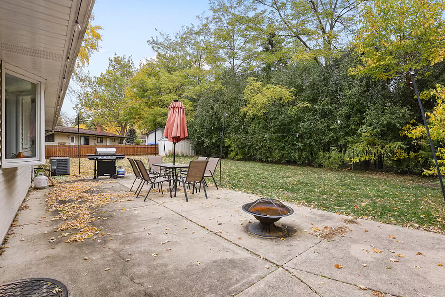 Outdoor patio table set with umbrella, grill and fire pit. Fenced backyard.