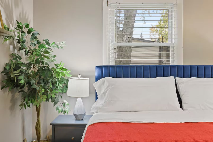 Bedroom 1 with king sized bed, sleeper couch, closet space and dedicated work table, chair and table lamp.