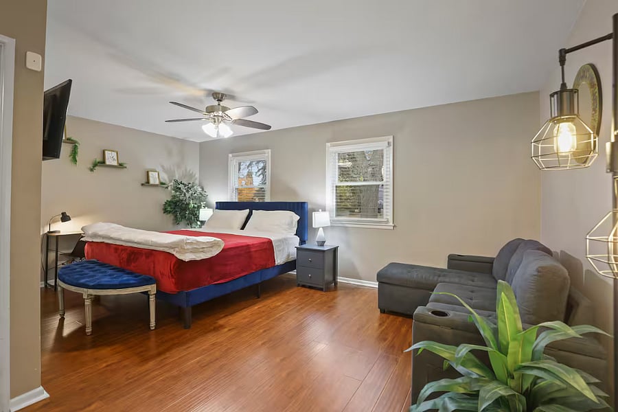 Bedroom 1 with king sized bed, sleeper couch, closet space and dedicated work table, chair and table lamp.