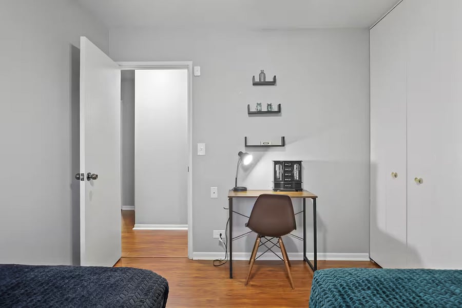 Bedroom 3 with 2 single beds, dedicated work space with table, lamp and chair and closet space.