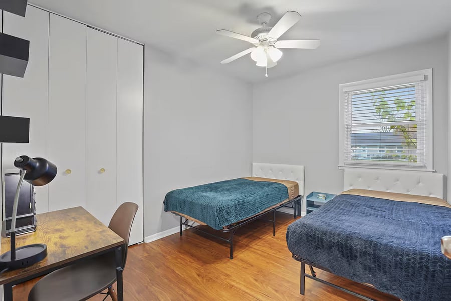 Bedroom 3 with 2 single beds, dedicated work space with table, lamp and chair and closet space.