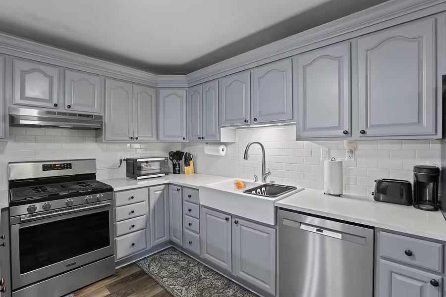Kitchen with a stove, oven, refrigerator, freezer, dishwasher, toaster, blender, and hot water kettle, cooking basics, baking sheets, dishes, silverware, wine glasses, and a coffee maker with coffee.