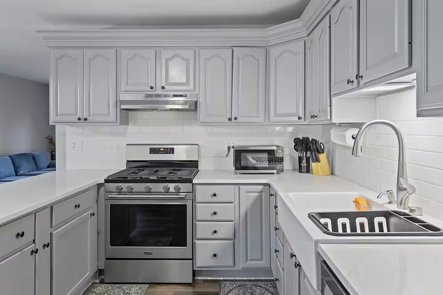 Kitchen with a stove, oven, refrigerator, freezer, dishwasher, toaster, blender, and hot water kettle, cooking basics, baking sheets, dishes, silverware, wine glasses, and a coffee maker with coffee.