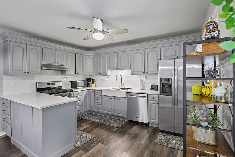 Kitchen with a stove, oven, refrigerator, freezer, dishwasher, toaster, blender, and hot water kettle, cooking basics, baking sheets, dishes, silverware, wine glasses, and a coffee maker with coffee.