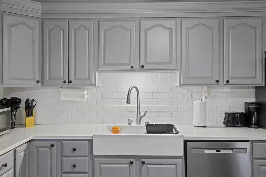 Kitchen with a stove, oven, refrigerator, freezer, dishwasher, toaster, blender, and hot water kettle, cooking basics, baking sheets, dishes, silverware, wine glasses, and a coffee maker with coffee.