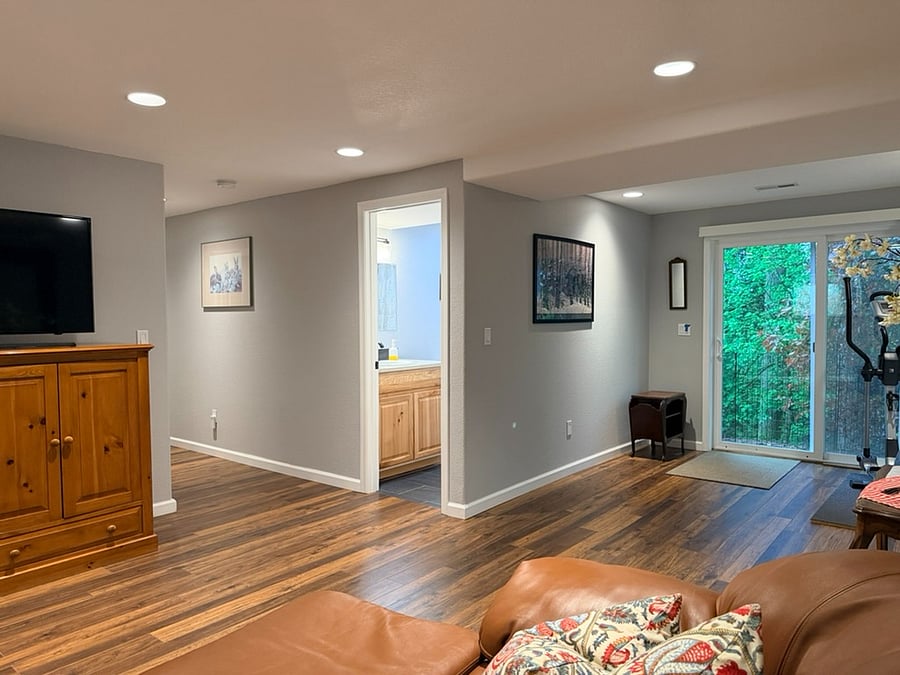 From Left to Right: TV and Storage Cabinet, Hallway to Private Queen Bedroom, Shared Laundry Room, and stairs to Shared Kitchen; Door to Private Bathroom; Private Entrance leading to 1-acre property's backyard and pathway to driveway, and Private Living Space!