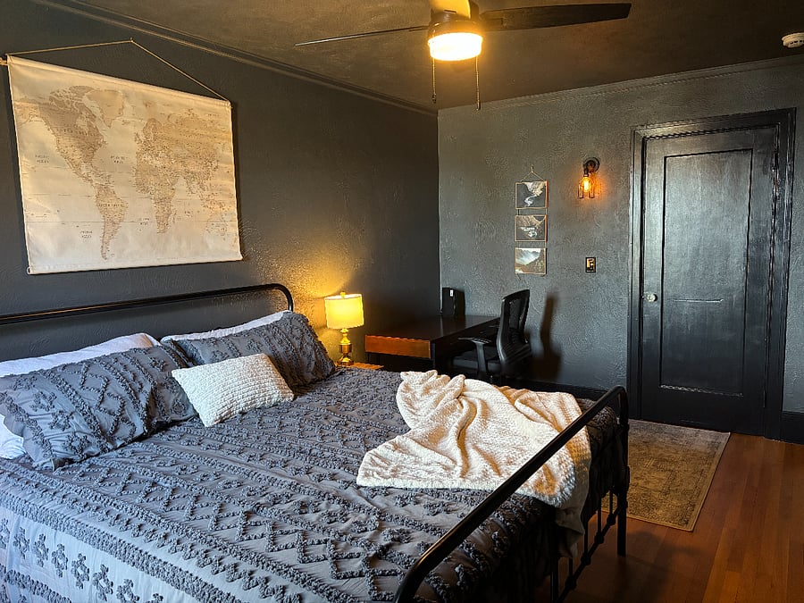 Master Bedroom w/ kind sized bed, blackout curtains, desk, office chair, & walk-in closet