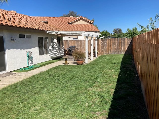 Backyard with patio and gas grill.  Sidewalk goes almost 360-degrees around the property.