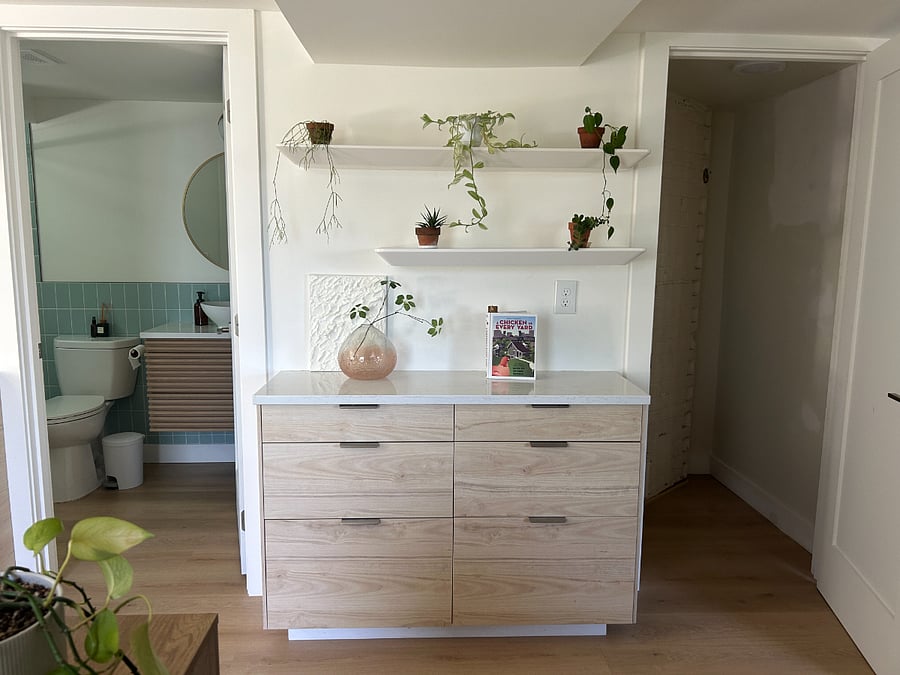 All drawers shown are available for storage. The door on the right leads to the bathroom, while the door on the left opens to a small closet. Floating shelves are suitable for light storage only.