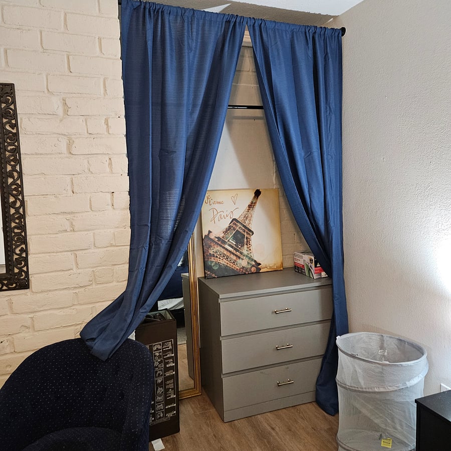 Closet area, including two drawer dresser and clothes hanging bar.