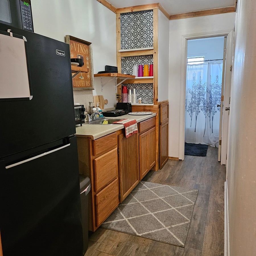 Kitchen showing location of fridge, plus the bathroom at the end of the room.
