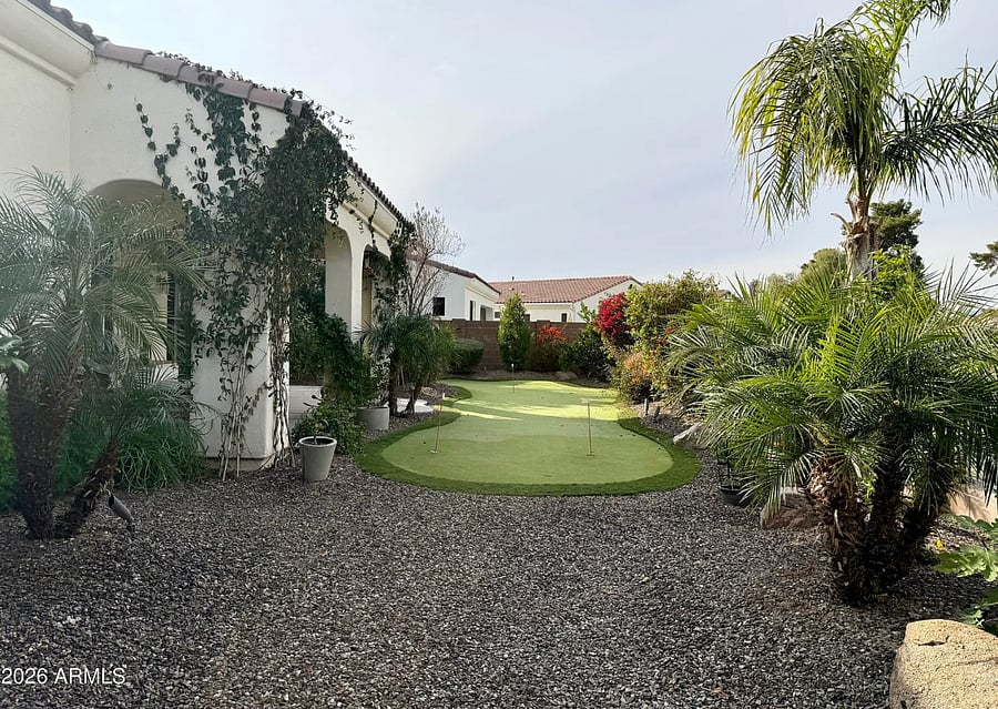Private outdoor putting green surrounded by mature landscaping.