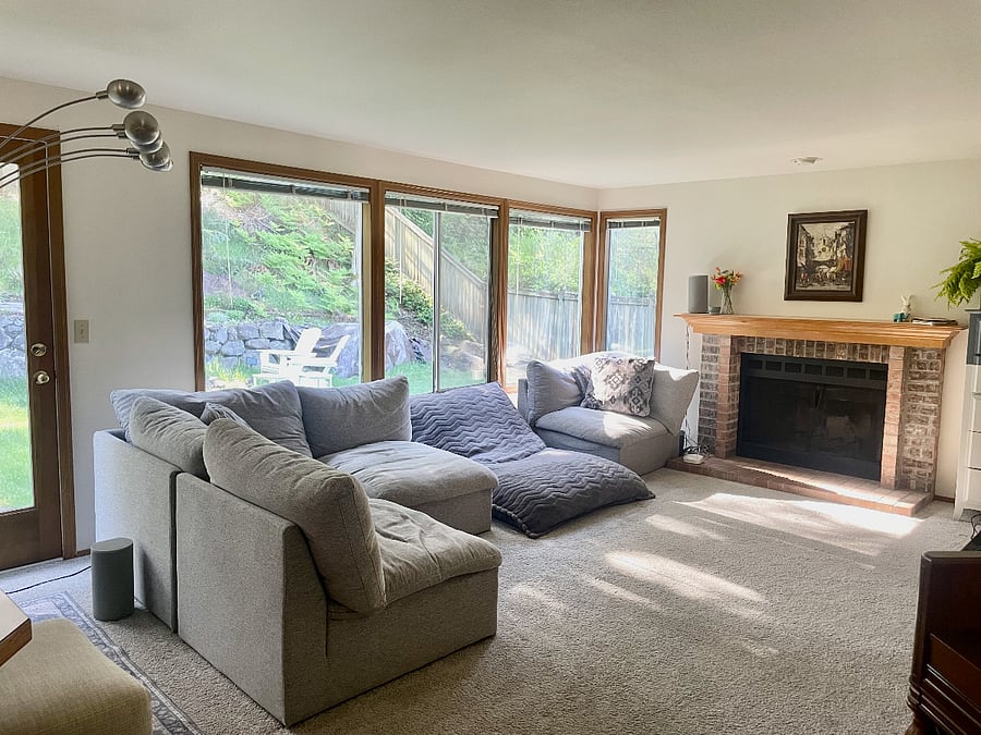 Large family room with ample lounging area and full of windows looking into the backyard.