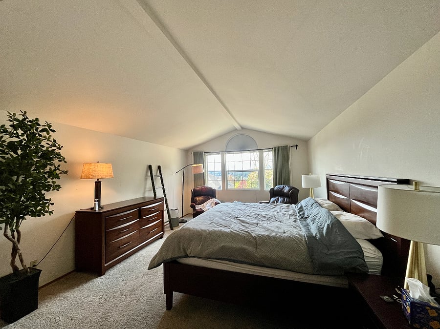 The primary bedroom featuring a vaulted ceiling, blackout curtains, and a large king bed.