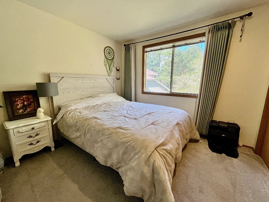 Moving to the secondary bedroom with a queen bed, blackout curtain and the window to the side of the back yard.