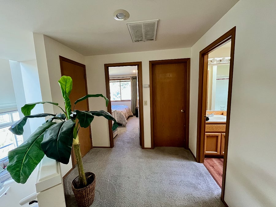 Moving upstairs, this is the hallway looking into the bedroom and the office. The leftmost door is a closet for towels. The next door to the right is the secondary bedroom. The next door to the right is the office. The rightmost door is the guest bathroom. The primary bedroom suite is located behind the photo taker.