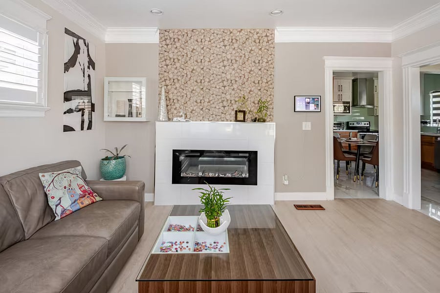 Living room: The organic leaf-textured tile accent wall with a built-in electric fireplace creates a cozy, stylish focal pointblending natural elegance with modern comfort. The perfect spot to relax after a day of exploring or unwind with a movie.