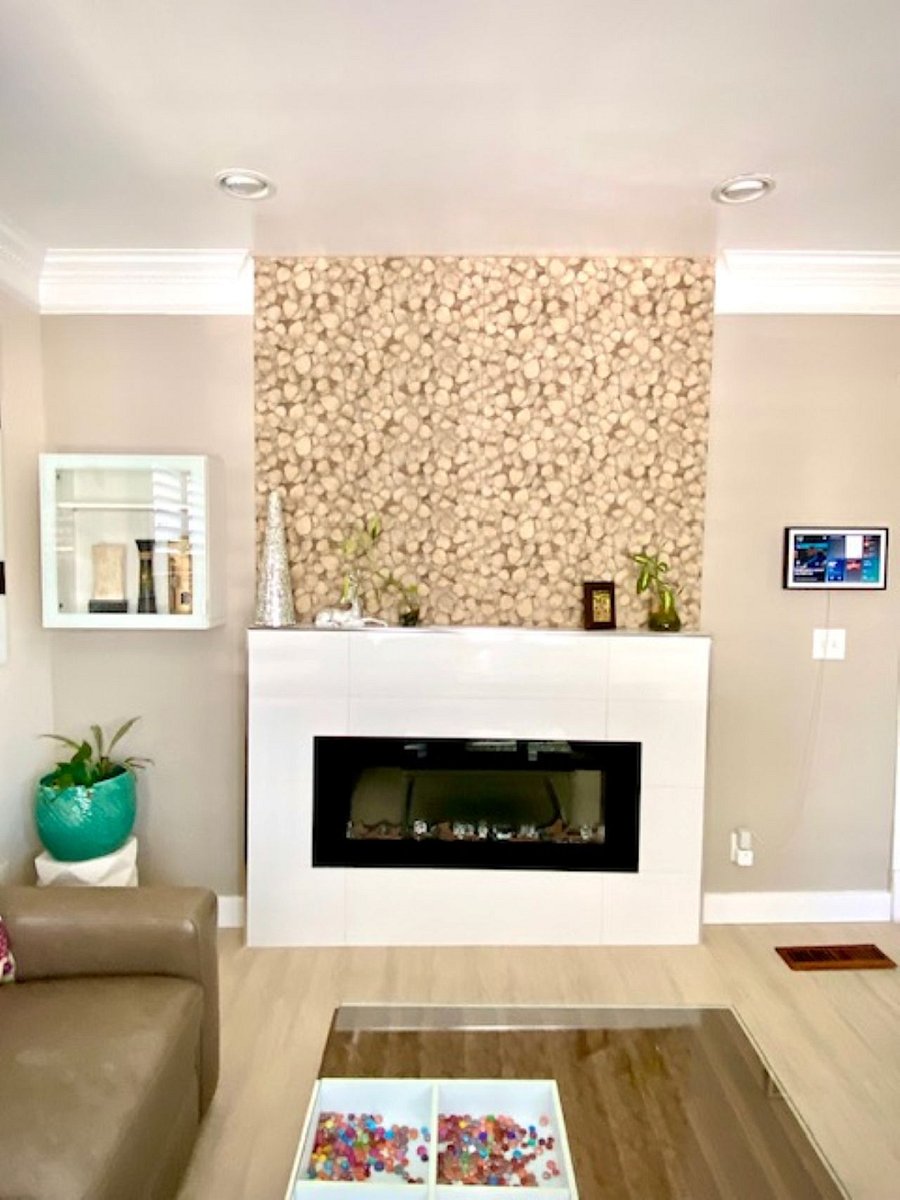 Living room: The organic leaf-textured tile accent wall with a built-in electric fireplace creates a cozy, stylish focal pointblending natural elegance with modern comfort. The perfect spot to relax after a day of exploring or unwind with a movie.